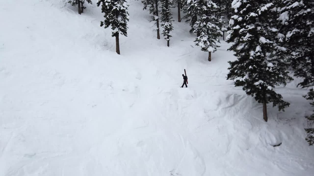 Skiier hiking up mountain takes a break in the snowfall