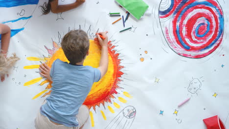 children drawing space theme on a large sheet of paper