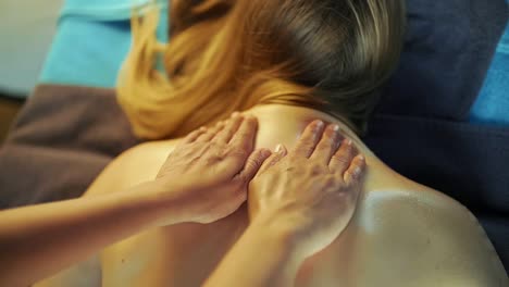 The-masseur-massages-the-girl's-back-with-massage-oil-from-bottom-to-top