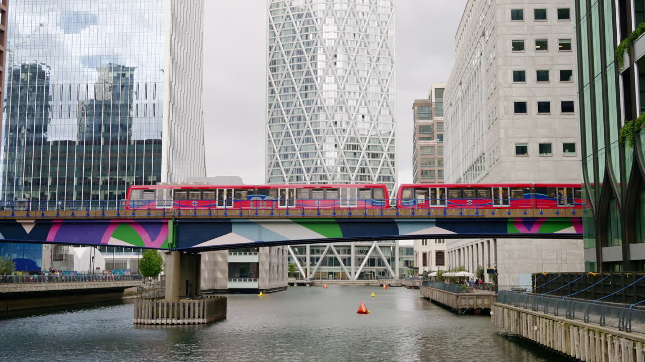 Street scape of the Canary Wharf district, water channels with train moving on a bridge, skyscrapers around in London, United Kingdom