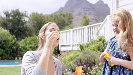 Mother-and-Daughter-blowing-bubbles-in-the-yard-happy-family-home