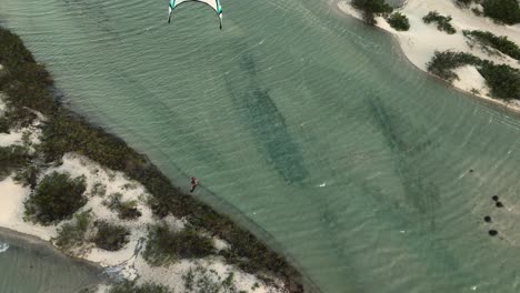 kiteboarder launches over coastal dune in lagoon and does kite loop