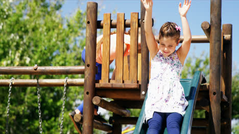 Glückliches-Schulmädchen,-Das-Auf-Der-Rutsche-Auf-Dem-Spielplatz-Spielt