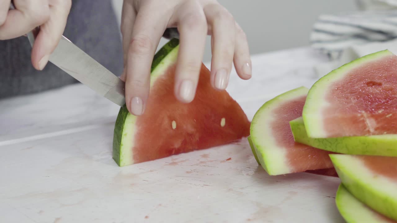 sandía roja sin semillas en una tabla de cortar blanca.
