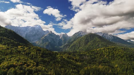 beautiful grand mountains valley italy, julian alps, aerial drone dolly, sunny green trees, blue sky with clouds, idyllic travel destination tourism, vacation location