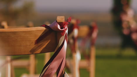 wooden chair decorated with pink ribbon on wedding venue