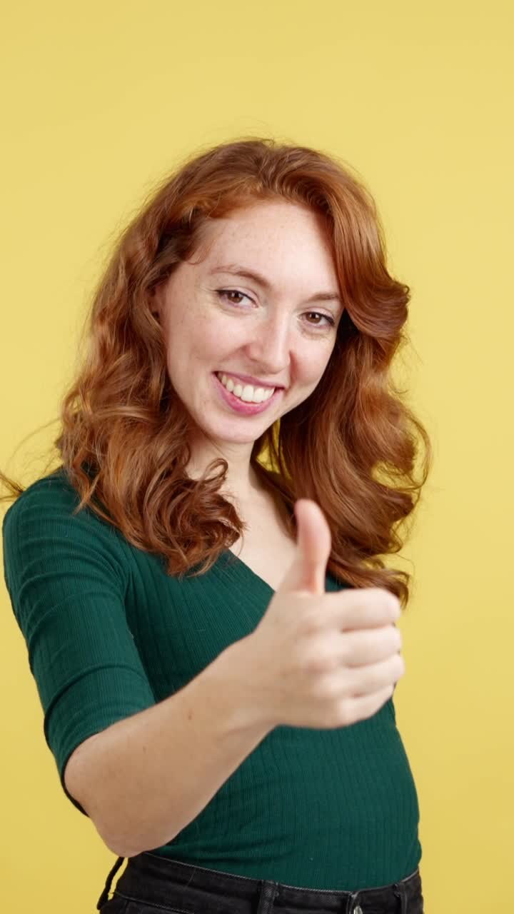 Donna sorridente con i capelli rossi che fa il gesto del pollice in su