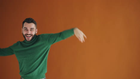 happy man dancing in front of orange wall