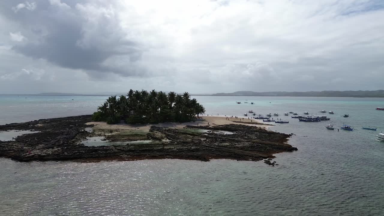 Orbit drone shot of a small island with coconut trees in the middle of the ocean