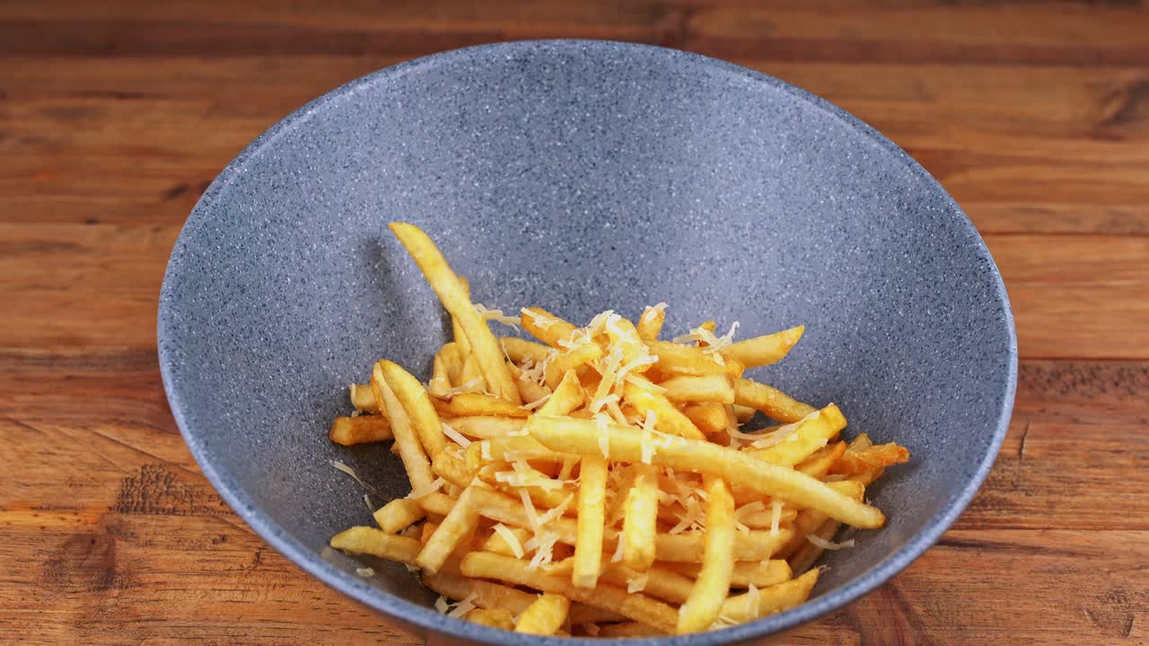 Detailed close up of grated cheese french fries being delivered to a table