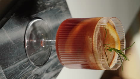 Vertikales-Video,-Das-Ein-Espresso-Tonic-Mit-Cold-Brew-Coffee,-Orangenscheibe-Und-Rosmarinzweig-In-Der-Heimischen-Küche-Präsentiert