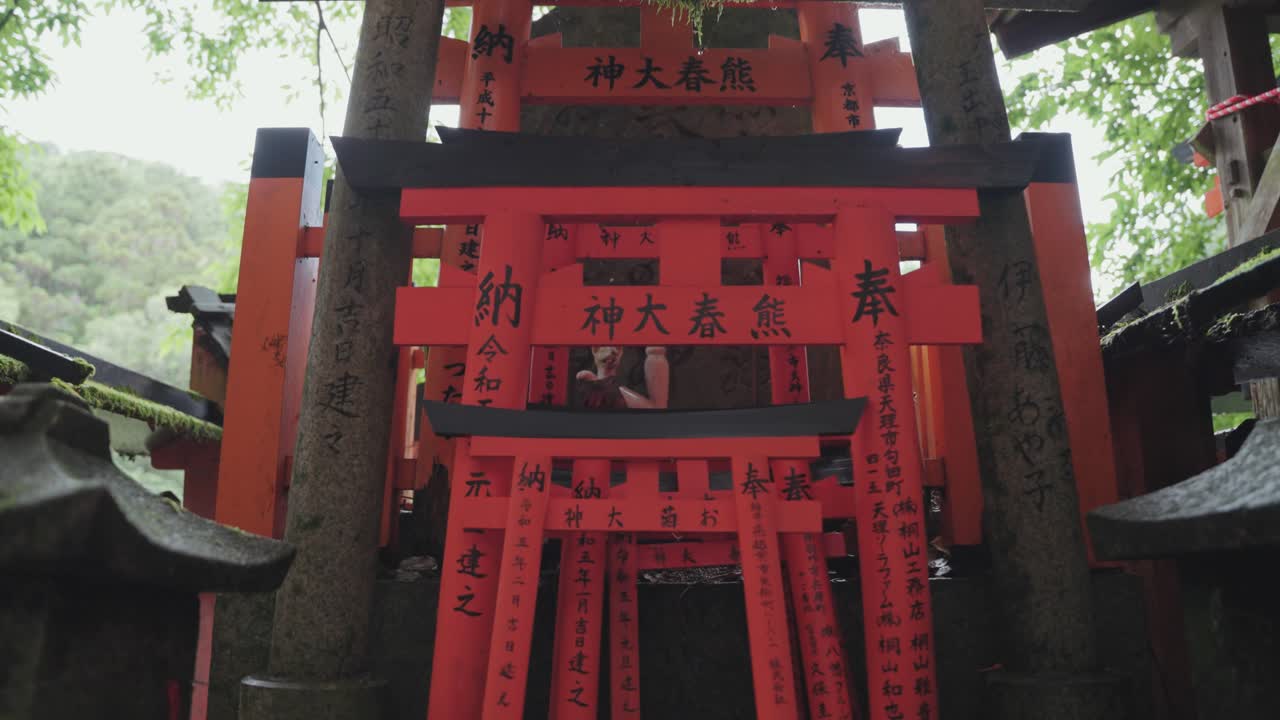 Detailed close-up of miniature torii gates at Fushimi Inari Shrine in Kyoto, each adorned with intricate Japanese writings, symbolizing prayers and wishes in a serene spiritual setting.