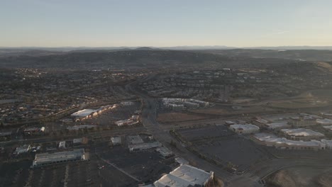 wideangle drone birdseye footage on a sunny misty morning over city streets of folsom, usa, with houses, buildings and streets in the foreground and mountains in the distance