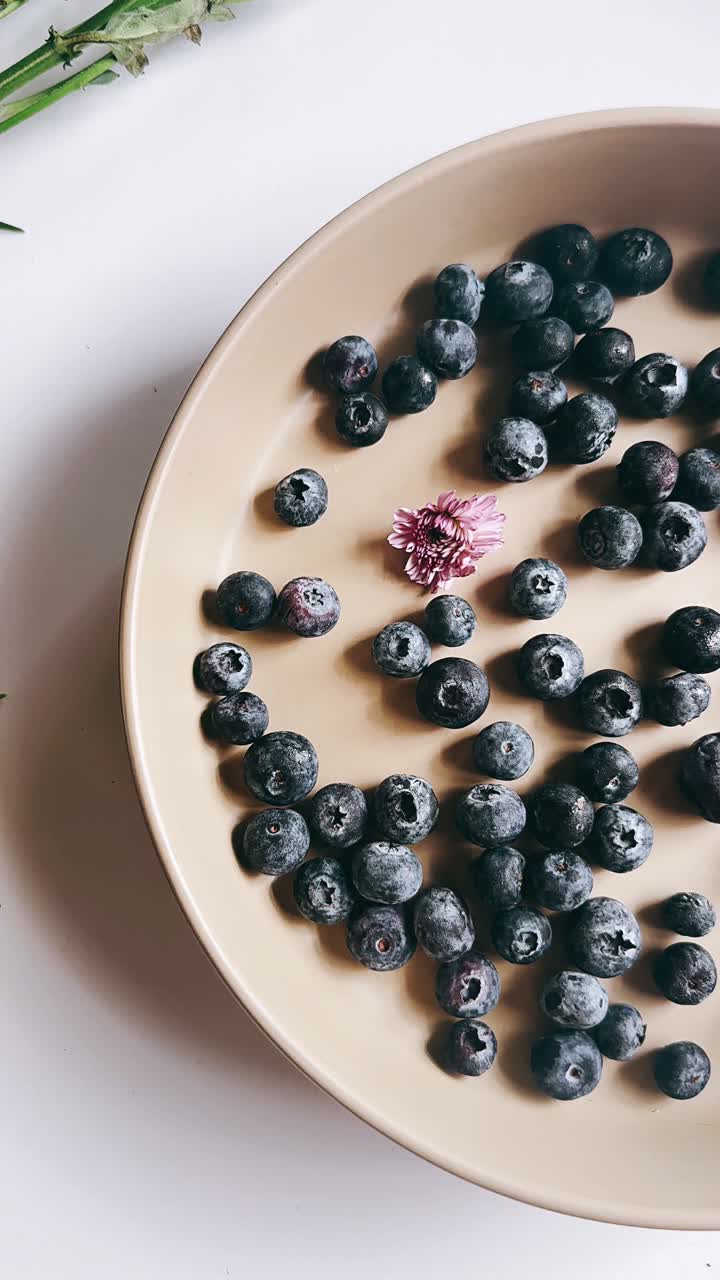 꽃 이 있는 베이지색 접시 에 있는 블루베리