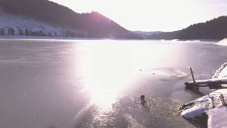 young man in frozen lake sits down in ice cold water