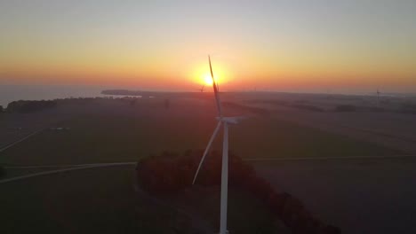windmill electricity generator farm wit a yellow and orange sunset in background