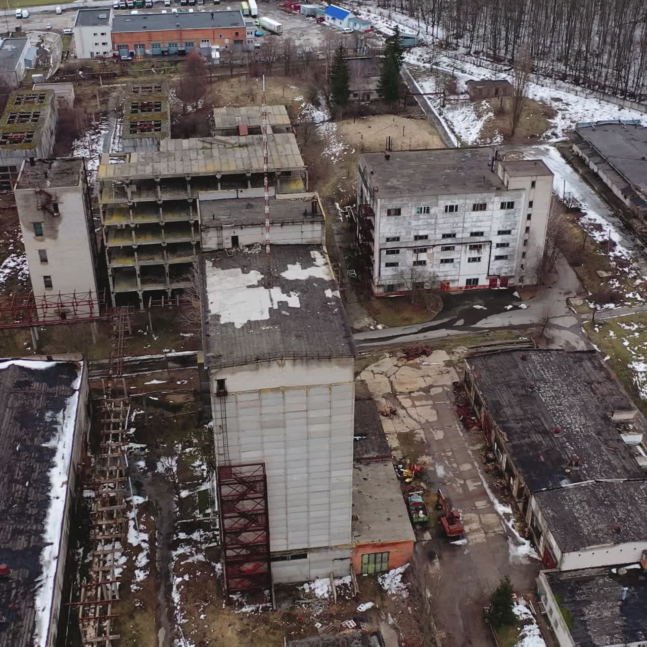 Aged factory with ruined buildings. Abandoned industry in dark background after the war. Aerial view. Orbital shot