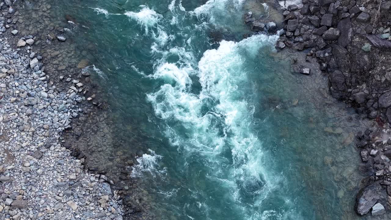 Vista aerea con drone di acqua turchese che scorre impetuosa attraverso un letto di fiume roccioso nel Montana, con rapide bianche che contrastano con rocce scure
