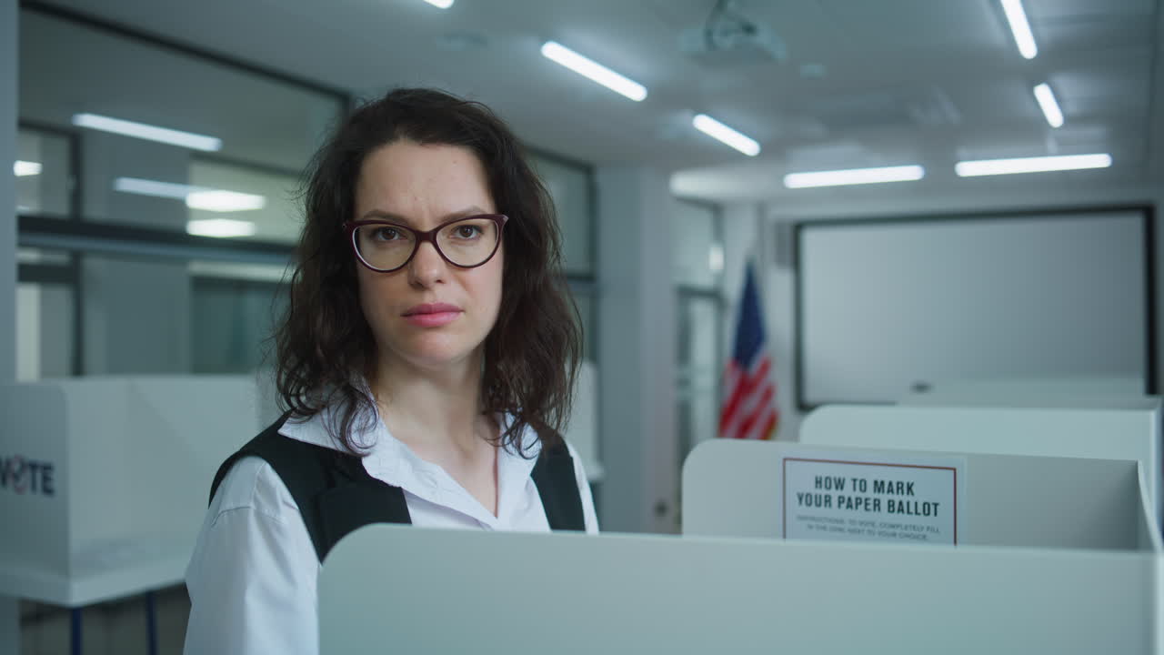 Close up of American Female Voter in Voting Booth Looking at Camera Close up of American Female Voter Choosing Presidential Candidate to Vote for in Voting Booth at Polling Station then Looking at Camera us Citizen during National Elections Day in the United States