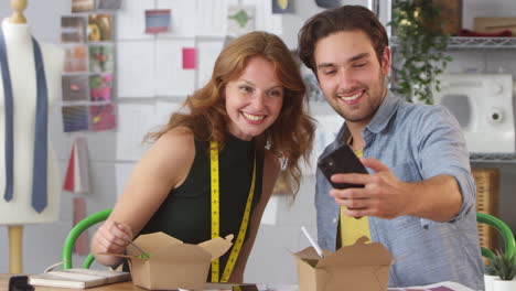 male and female fashion designers taking selfie on mobile phone during takeaway lunch