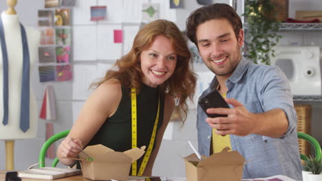 diseñadores de moda masculinos y femeninos tomando selfies en el teléfono móvil durante el almuerzo para llevar