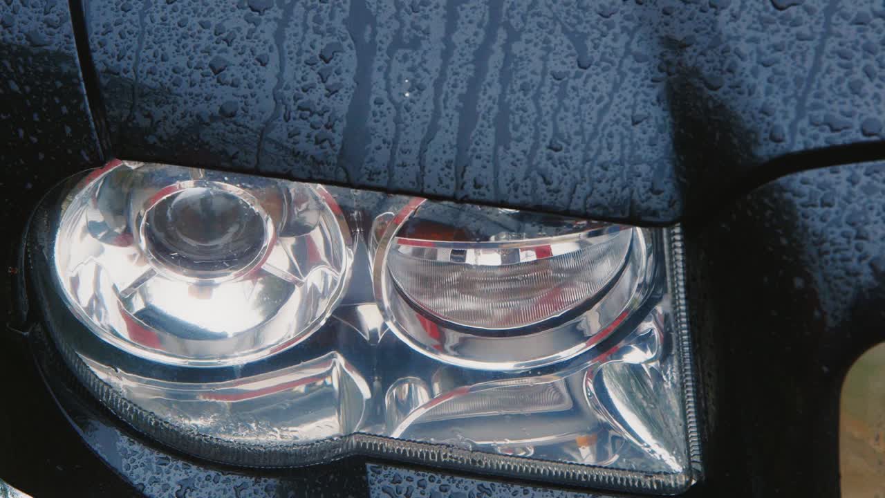 유리 아래로 떨어지는 비 빗방울의 자동차 헤드 라이트