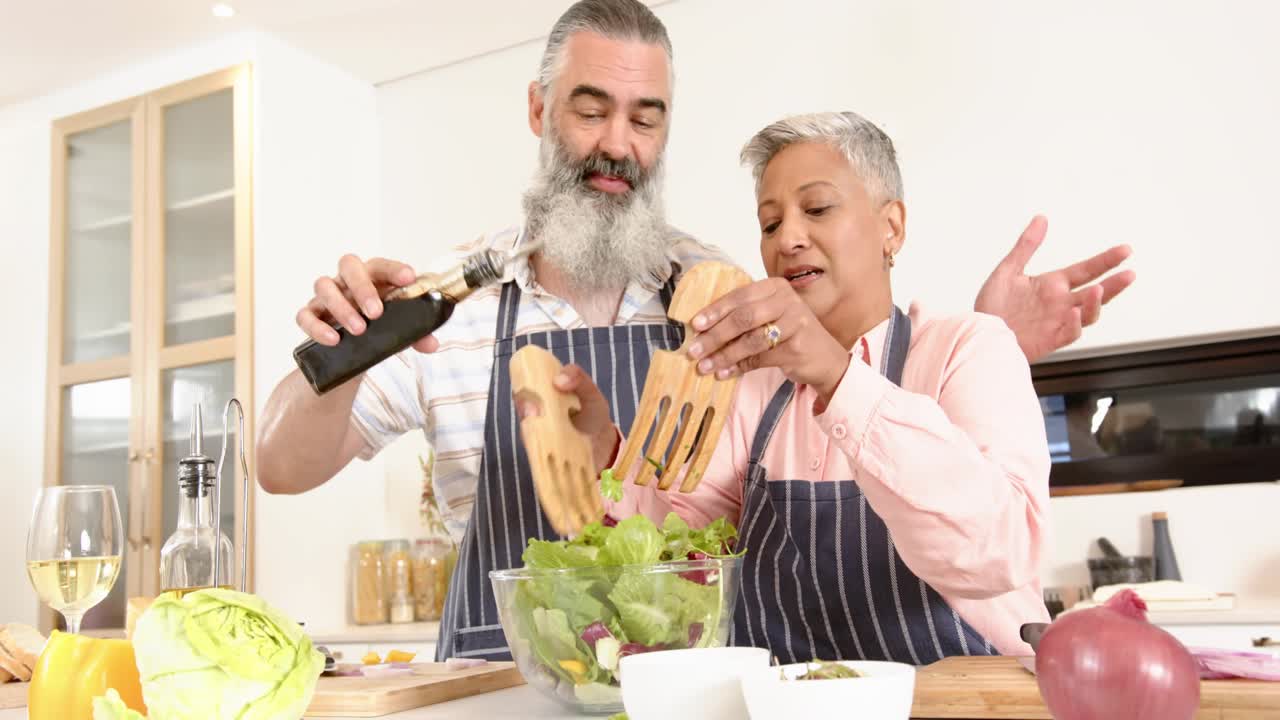 Man pouring oil and woman tossing salad at kitchen island, animated UI icons guiding salad prep