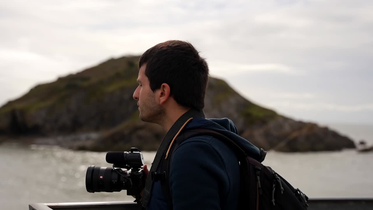 Un fotografo che ammira il paesaggio a Bracelet Bay dal Molo di Mumbles.