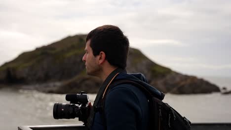male photographer admiring the landscape in bracelet bay from mumbles pier