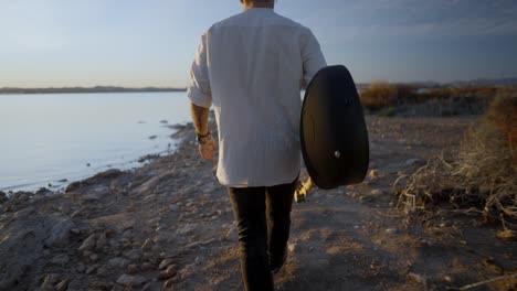 man with guitar at sunset lake