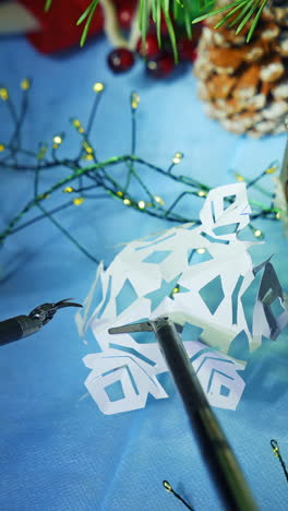 gadget humanoid preparing snowflake from paper while preparing to the christmas. cropped view. future technologies concept. vertical video