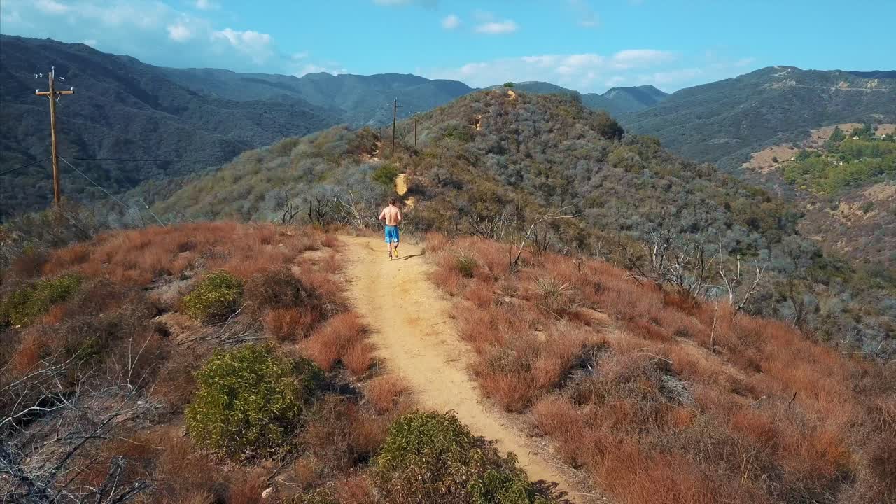 hombre aéreo corriendo en la cima de la montaña