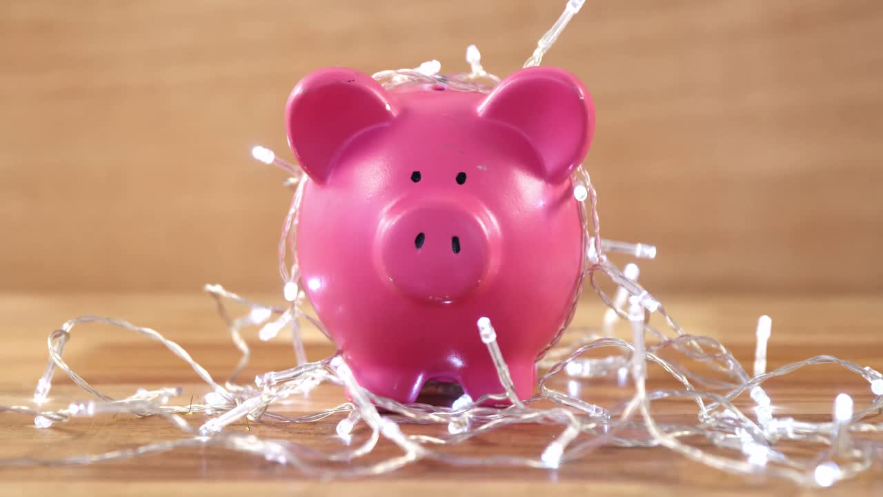 Piggy bank with fairy lights on wooden table