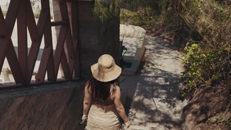 girl in a hat walking down the stairs of a tropical hotel resort