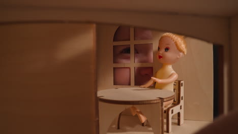 smiling little child peeks into window at small doll in room