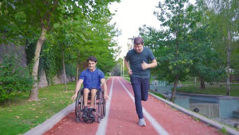 adolescente discapacitado haciendo deportes en silla de ruedas y su amigo acompañándolo.