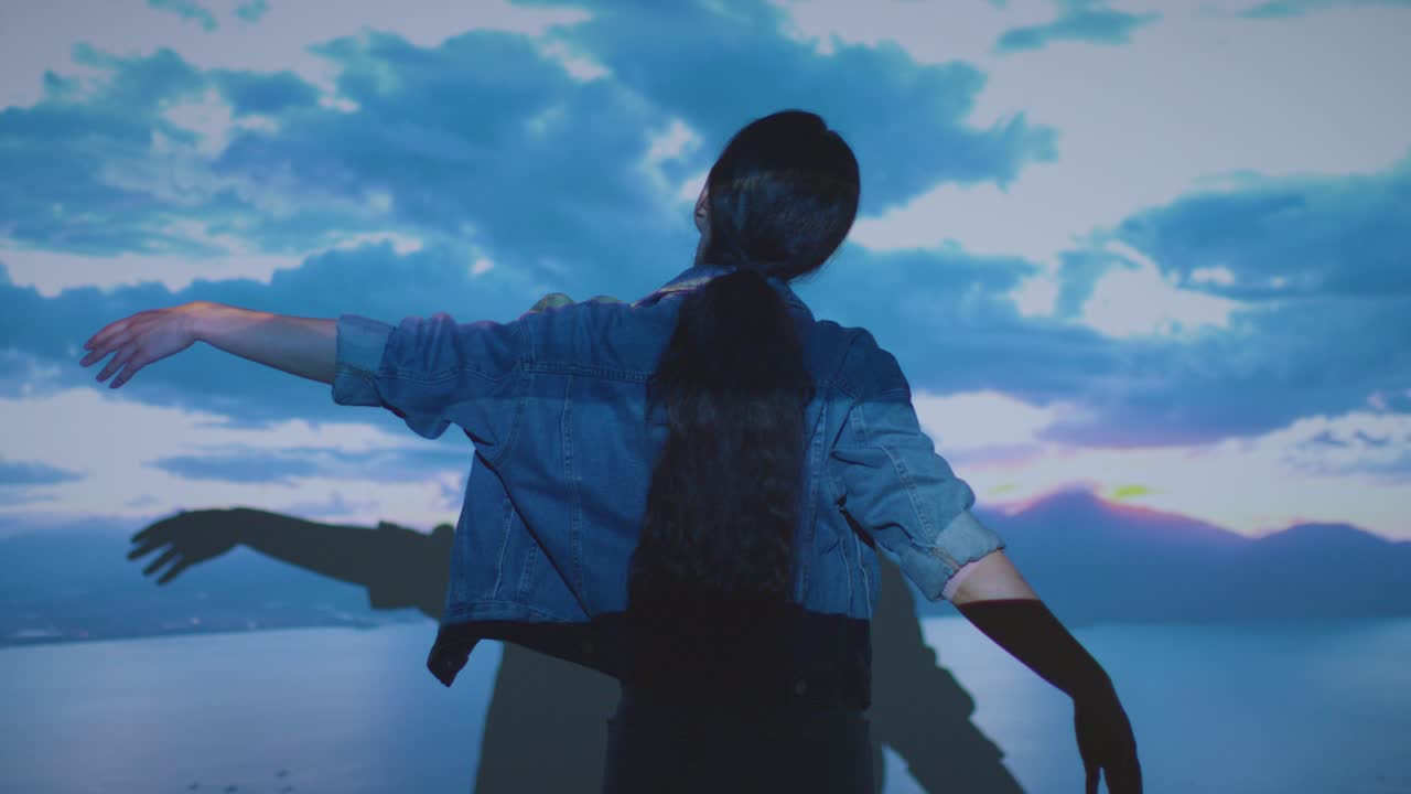 женщина посещает художественную выставку, взаимодействуя с изображениями облаков, проецируемыми на стену.