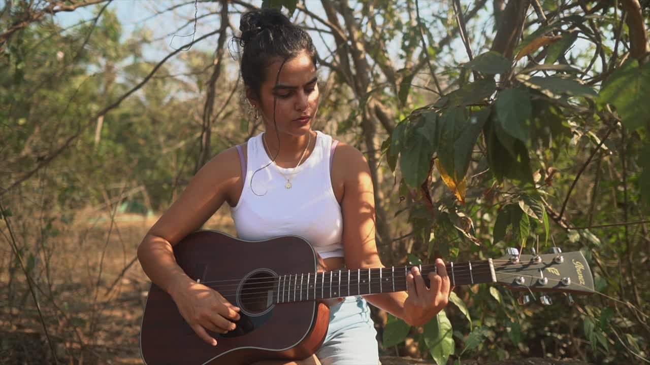 attraente ragazza indiana che suona la chitarra in una camicia,