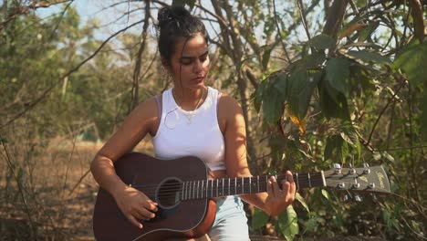 attractive indian girl playing the guitar in a shirt,