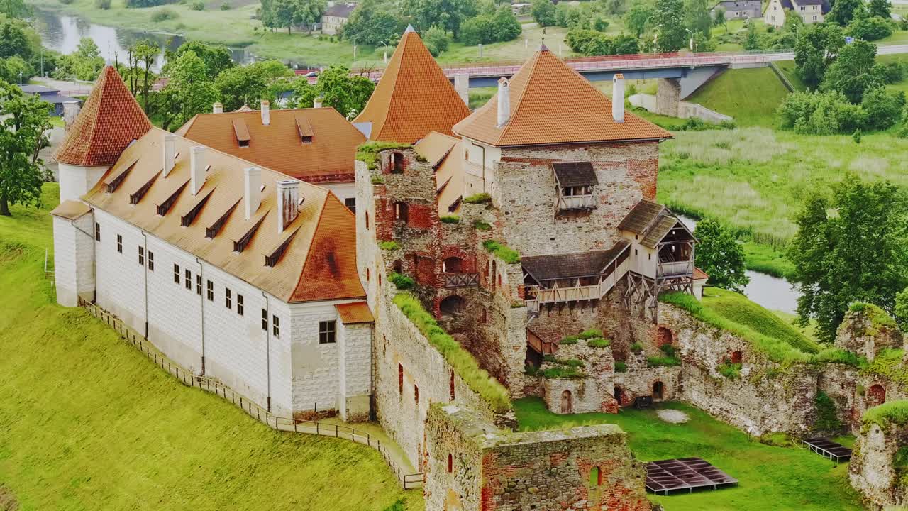 Aerial drone circle reveals historic Bauska Castle ruins in cloudy weather