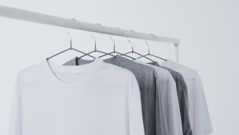Video-Von-Weißen-Und-Grauen-T-Shirts-Auf-Kleiderbügeln-Und-Kopierraum-Auf-Weißem-Hintergrund