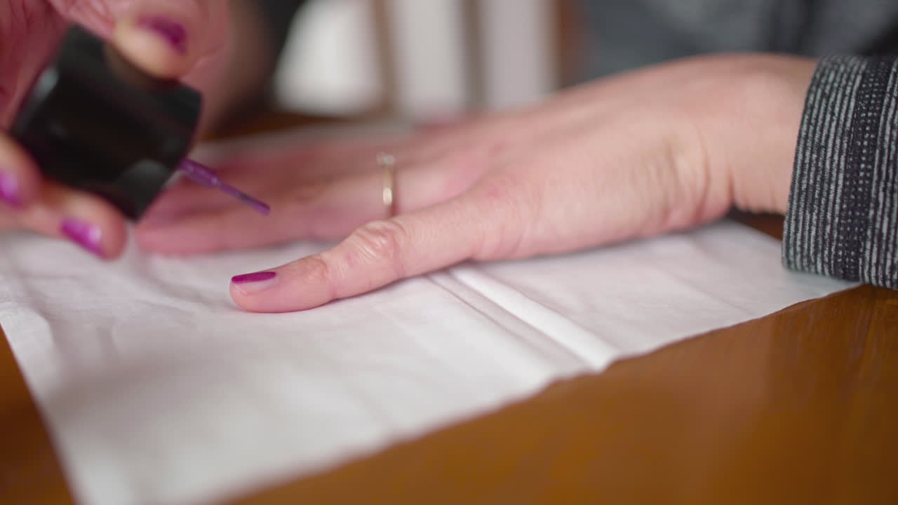 женщина наносит лак для ногтей на мизинец через салфетку, надевая обручальное кольцо
