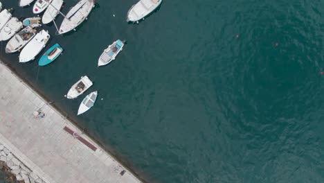 Top-Down-Drohne-Schoss-Auf-Einen-Steinpier-Und-Verankerte-Boote