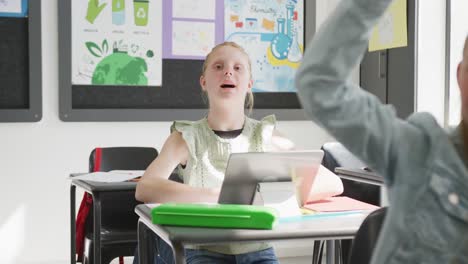 Video-of-attentive-caucasian-schoolgirl-at-desk,-raising-hand-and-talking-in-class,-copy-space