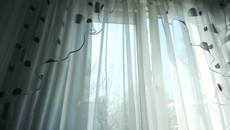 la cortina blanca transparente se mueve contra el viento desde una ventana abierta