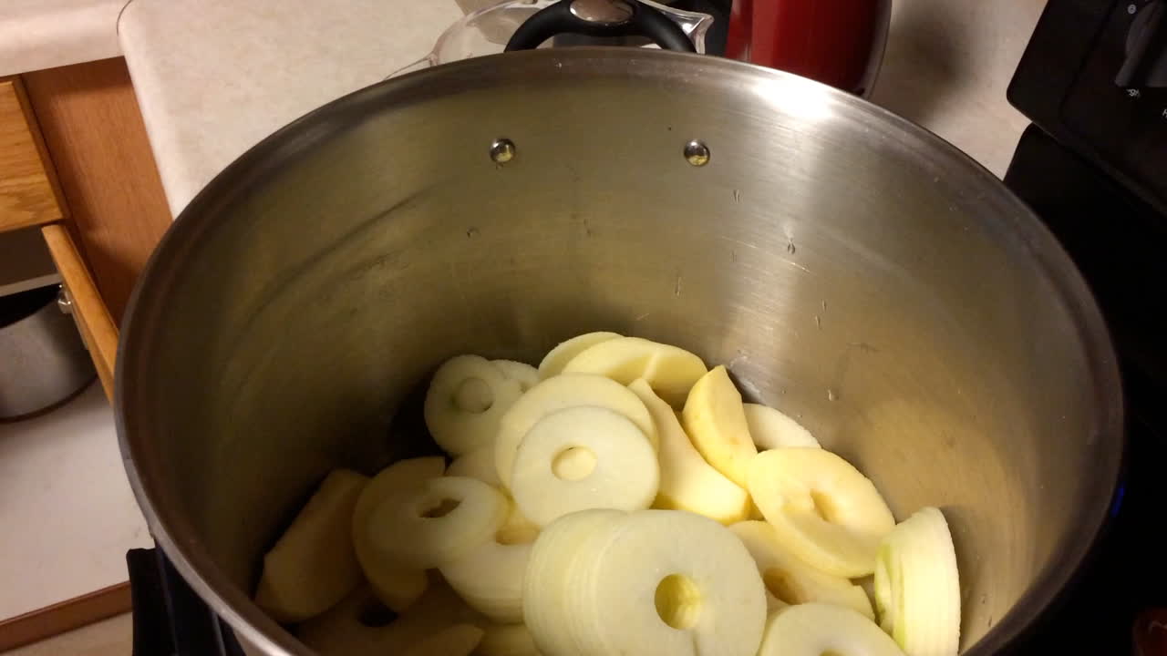 Putting peeled apples in pan for applesauce in kitchen