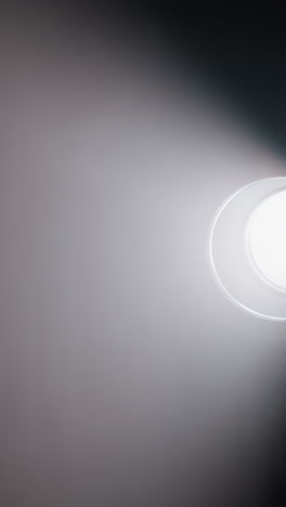 reflector de estudio proyectando un fuerte haz de luz a través de una habitación oscura, destacando el humo y la atmósfera