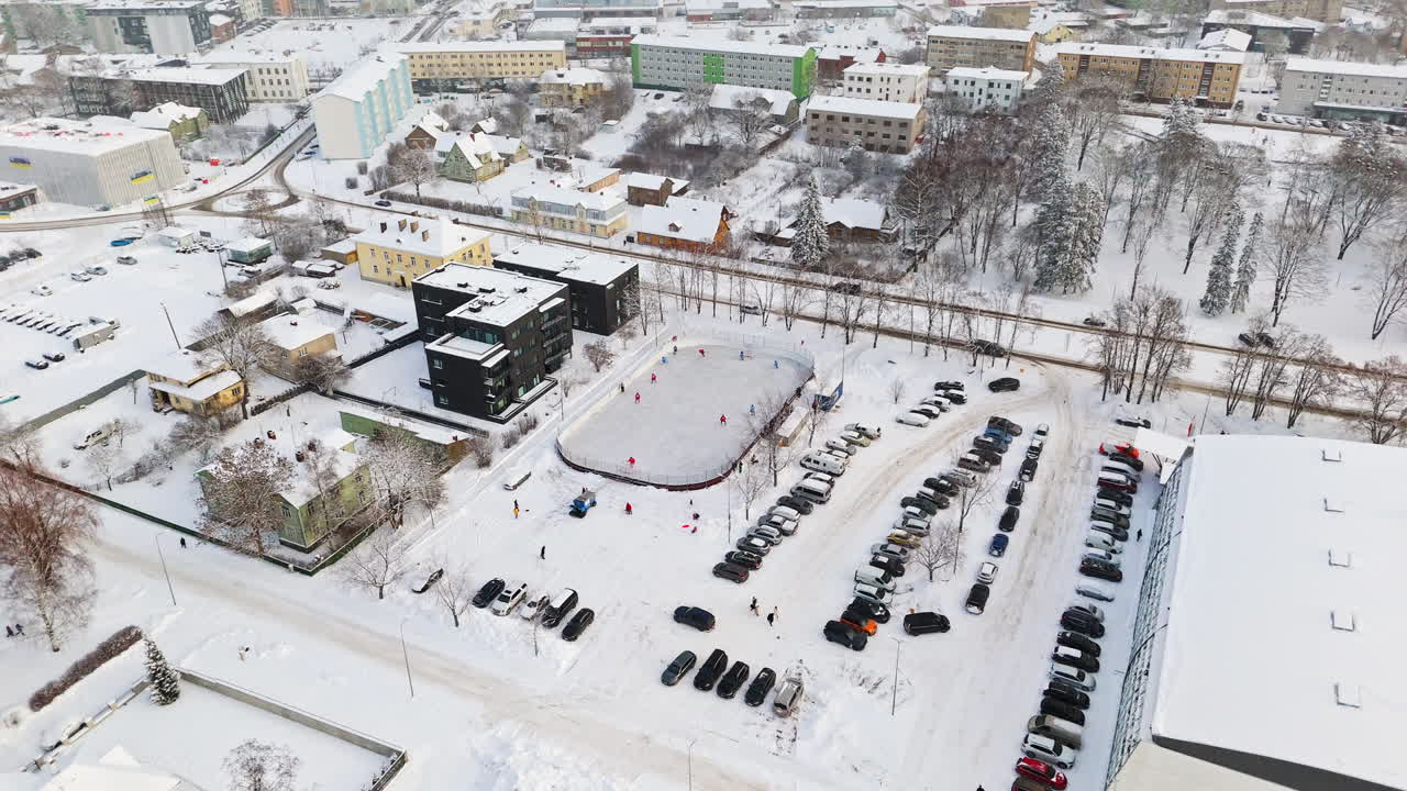 Panoramic drone shot circling a ice hockey game at a outdoor rink winter day