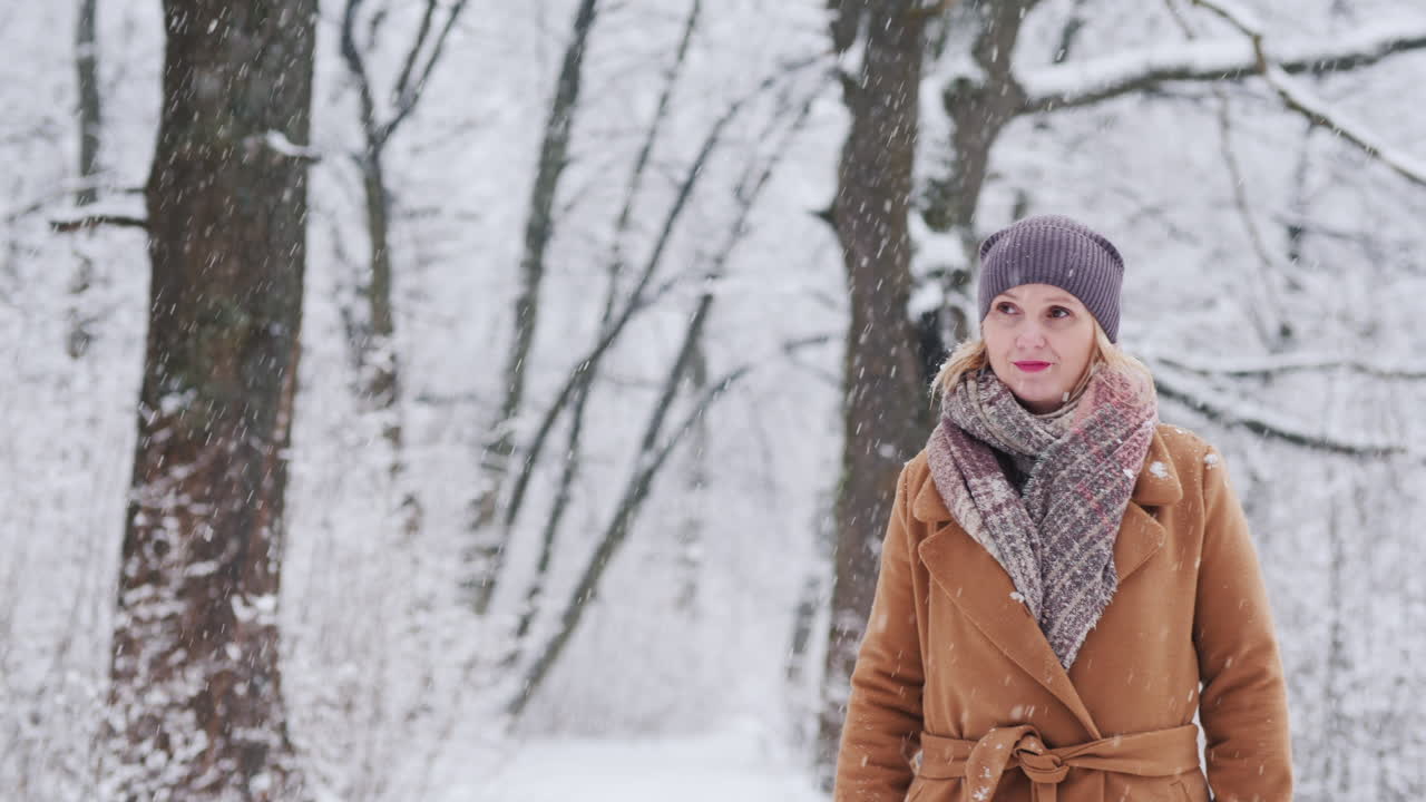 mujer joven atractiva camina en el bosque de invierno cubierto de nieve