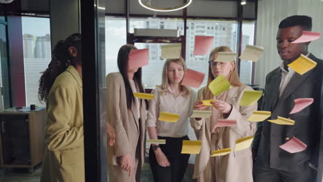 creative team of young specialists work in office discuss idea and sticking notes on glass wall